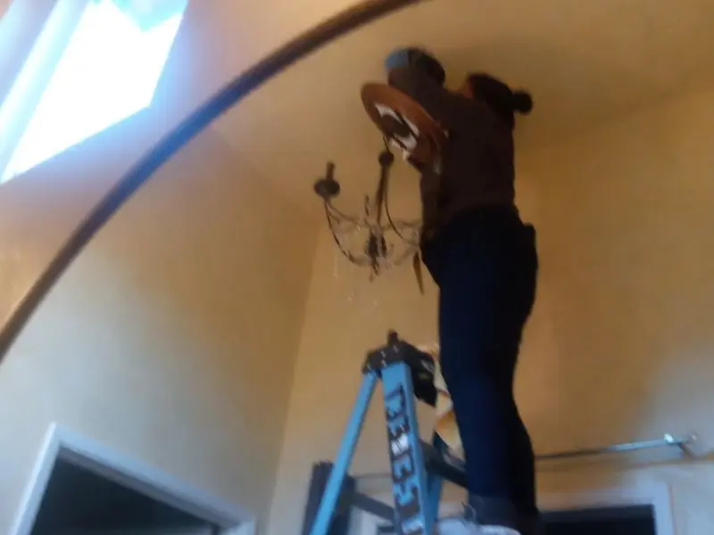 Electrician installing a chandelier in a Bryan residence